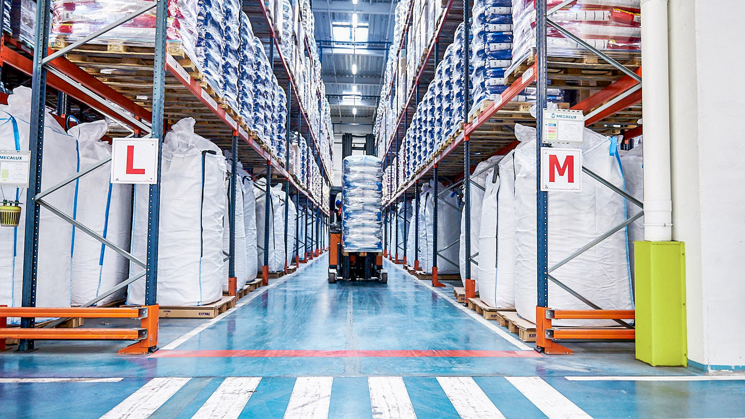 A forklift truck carrying a stack of products through a warehouse