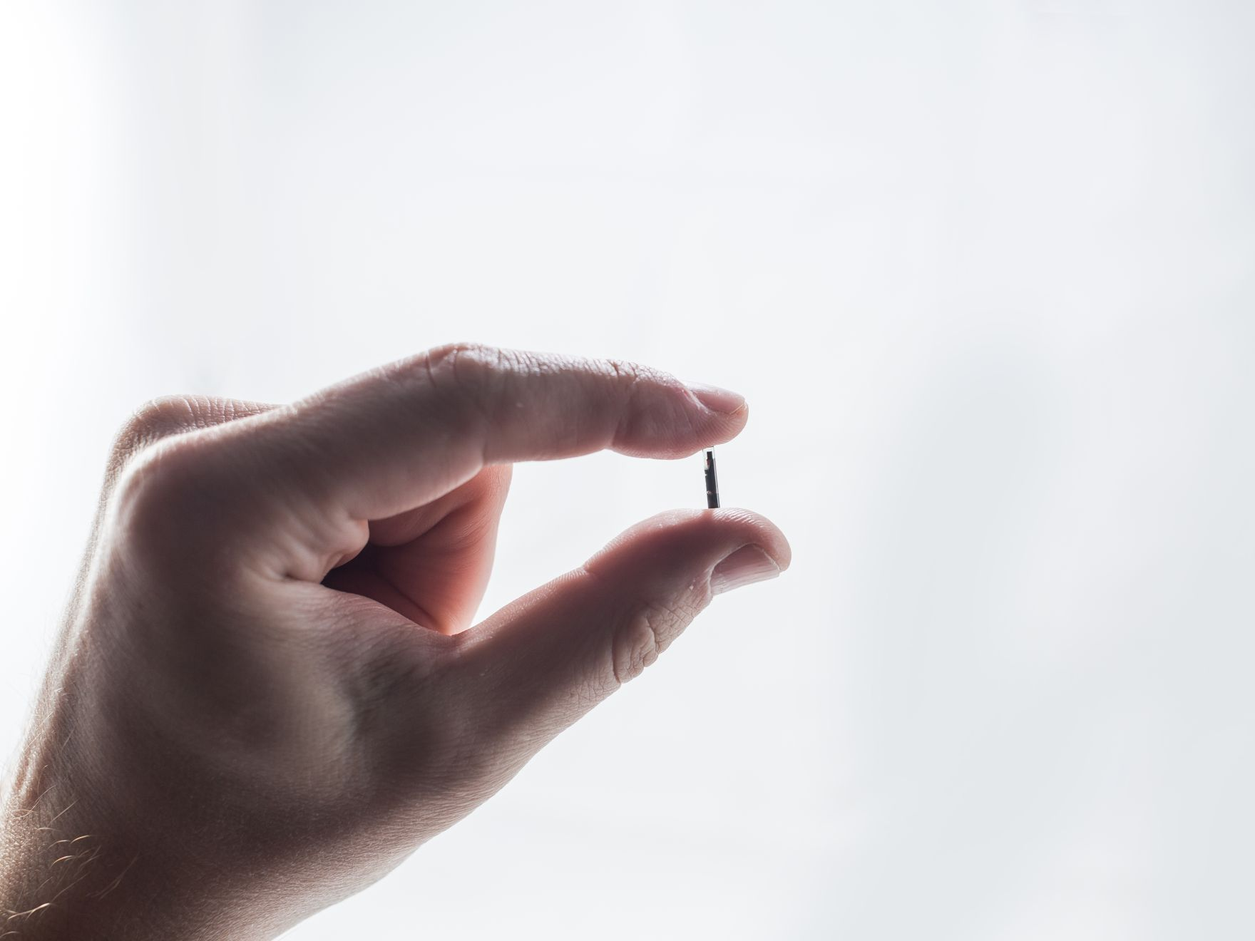 microchip in hand on light background