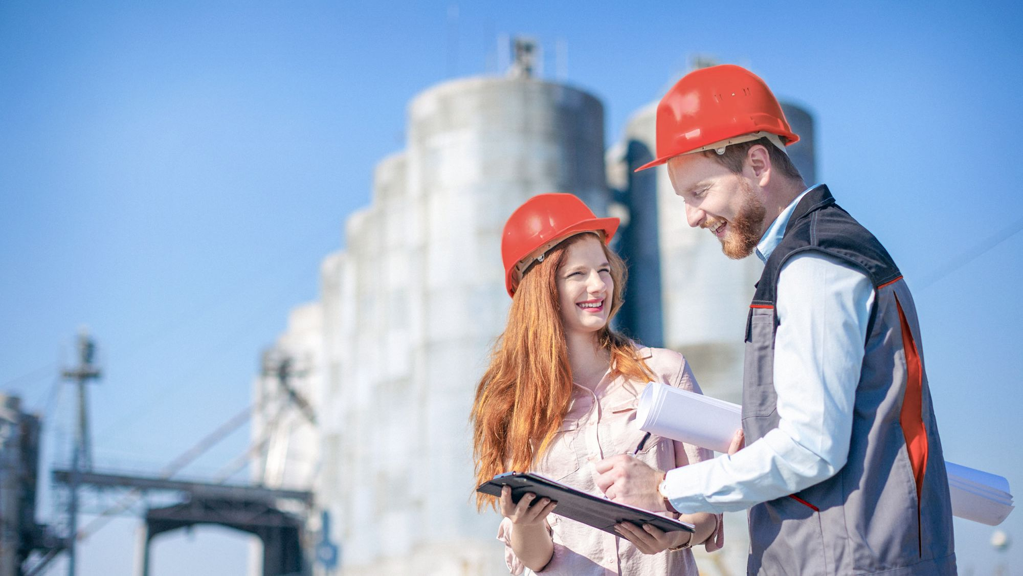 Two workers stood outside a factory checking a clipboard