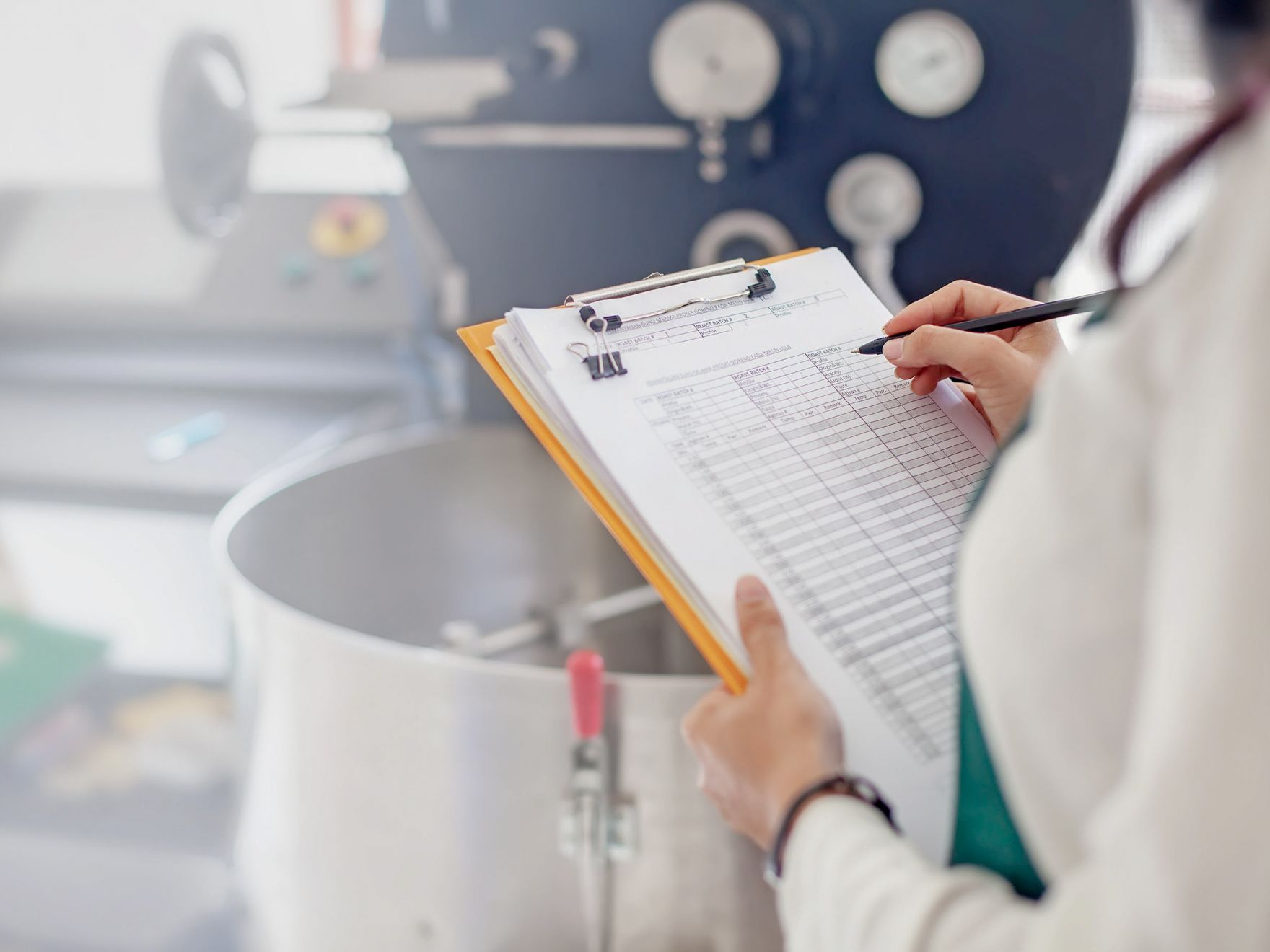 A woman in a factory checking a clipboard